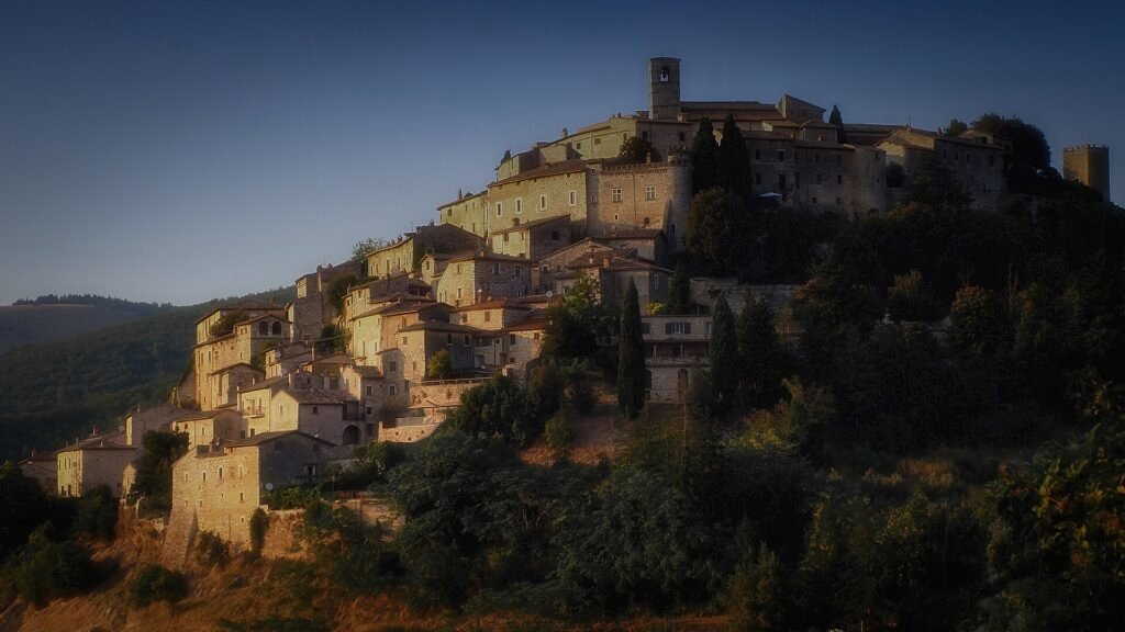 Il borgo di Labro in cima al colle, case di pietra raccolte sotto la torre del castello, nella luce calda della sera
