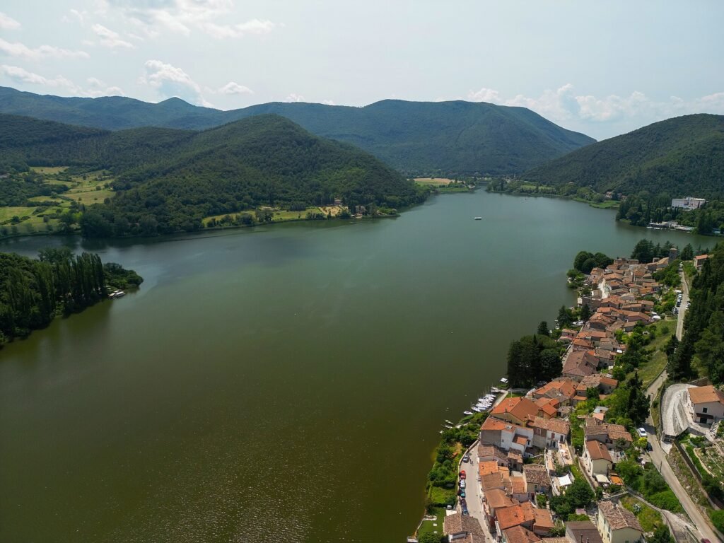 Veduta aerea del Lago di Piediluco tra colline verdi, con i tetti del paese lungo la riva destra