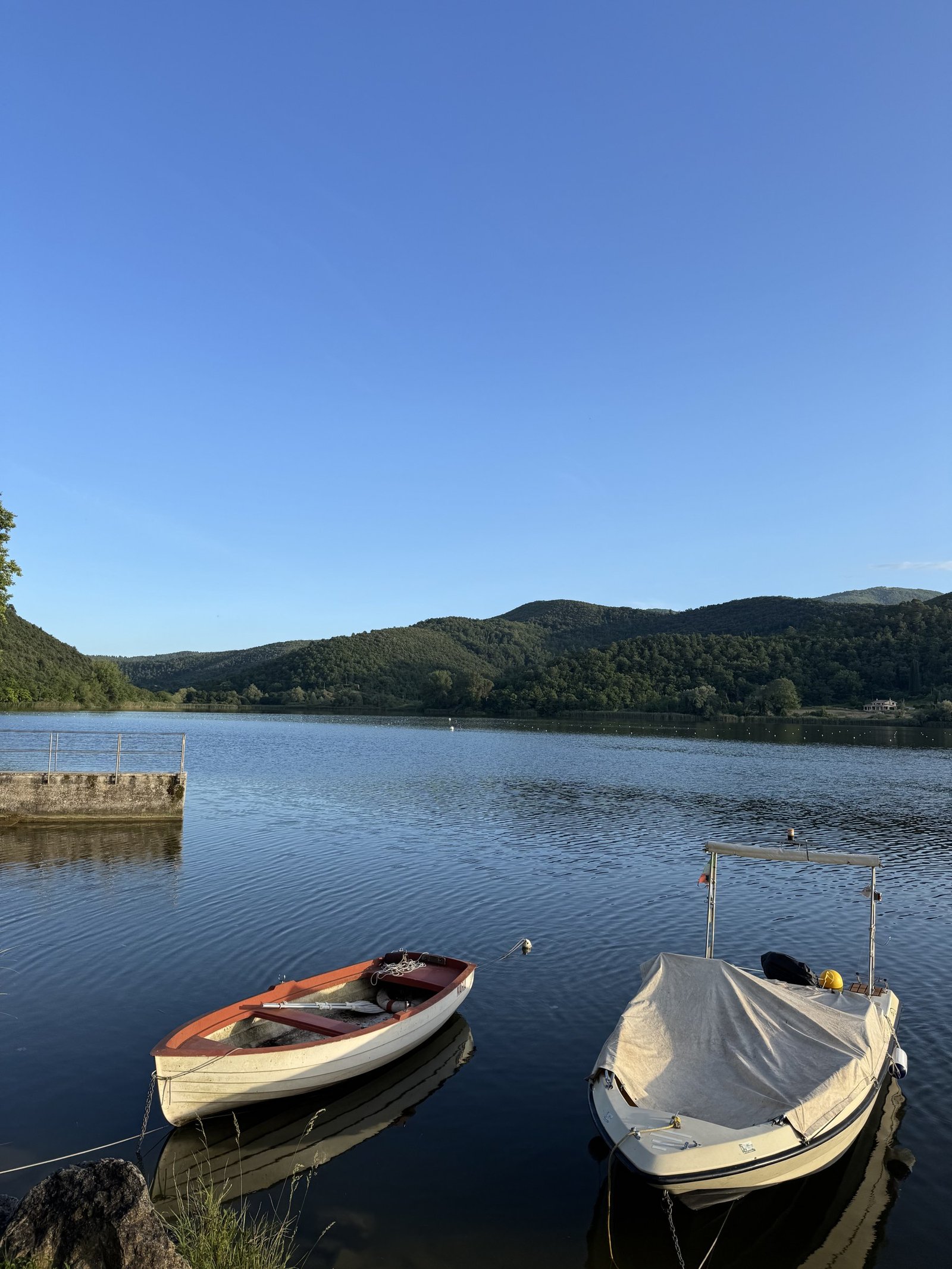 Boats moored on Lake Piediluco beneath wooded hills