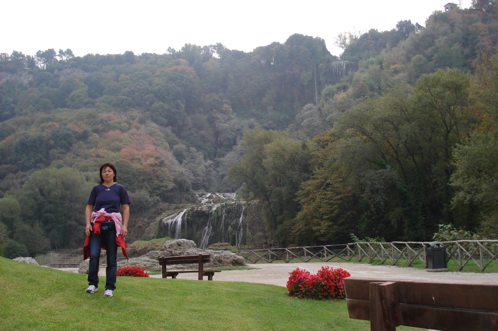 The Marmore Falls cliff with almost no water flowing, seen from a lawned viewpoint with benches