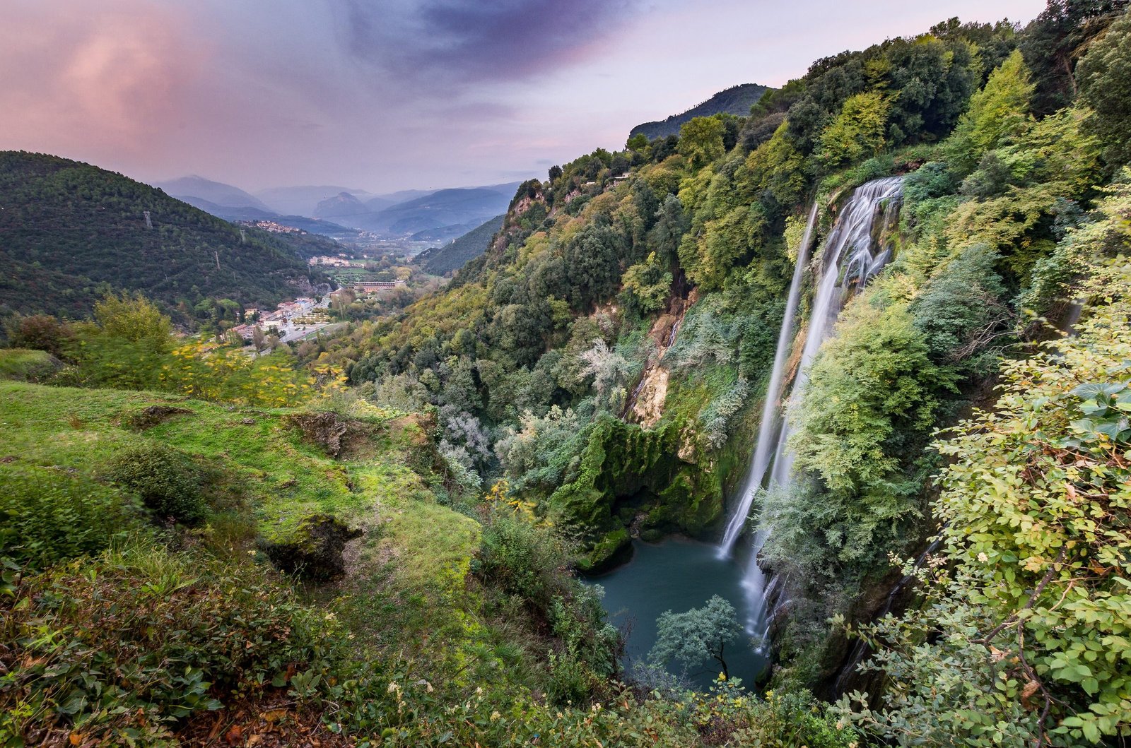 The Marmore Falls seen from a distance in the wider valley landscape under a dramatic sky