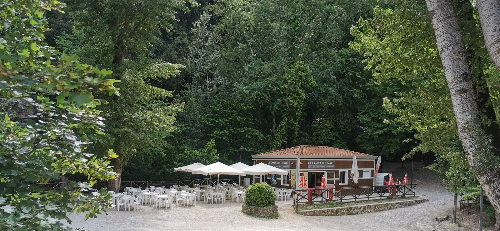An outdoor cafe terrace with white parasols among trees in the Marmore Falls park