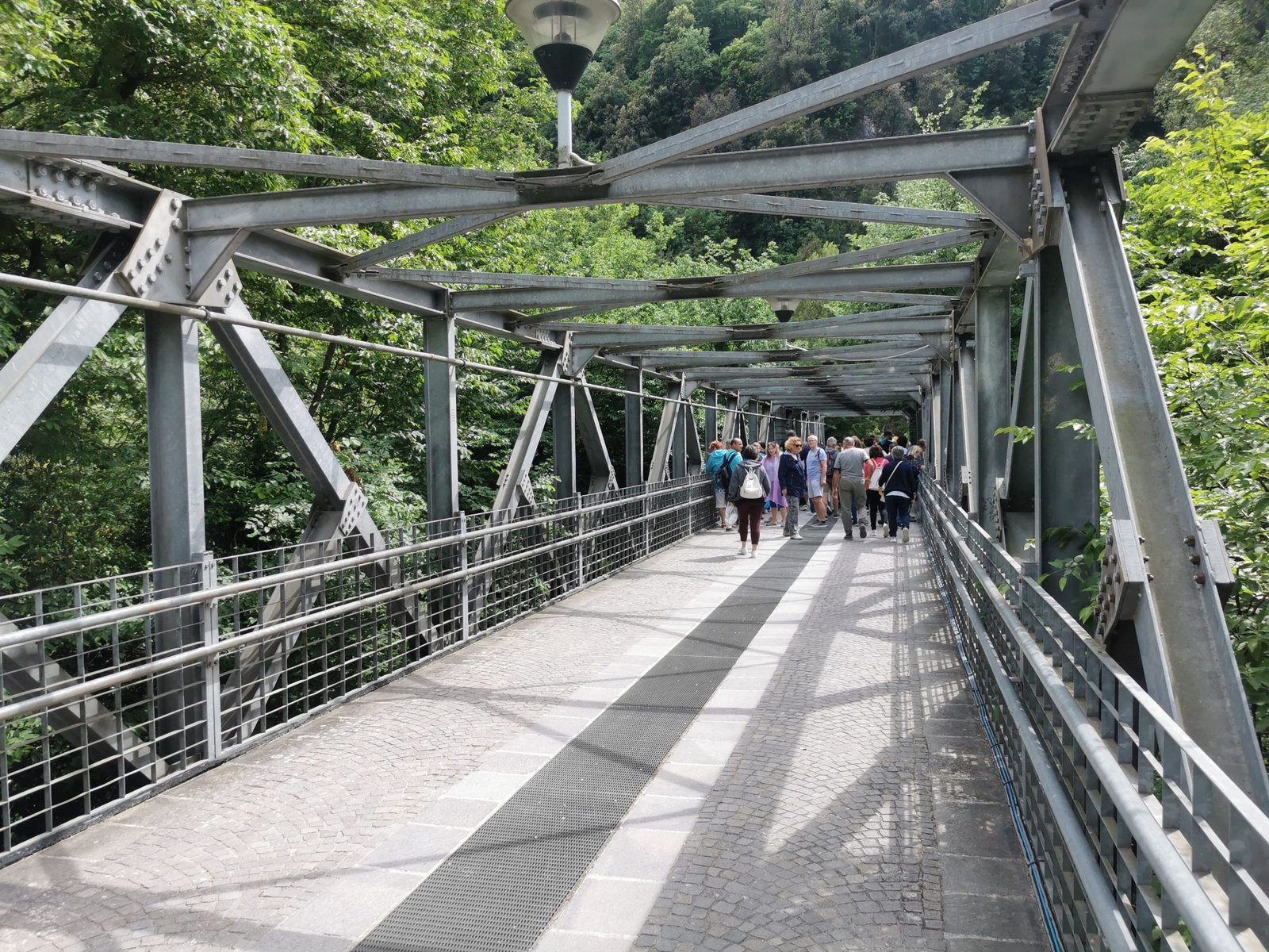 Visitors crossing a steel footbridge in the Marmore Falls park
