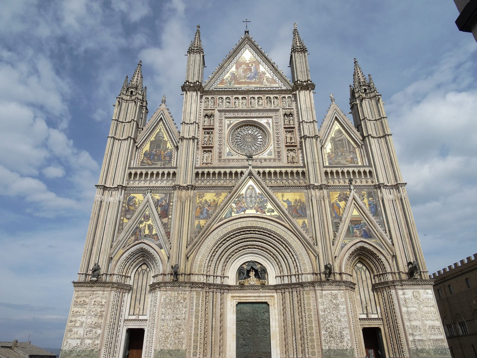 The striped Gothic facade of Orvieto cathedral with its gold mosaics
