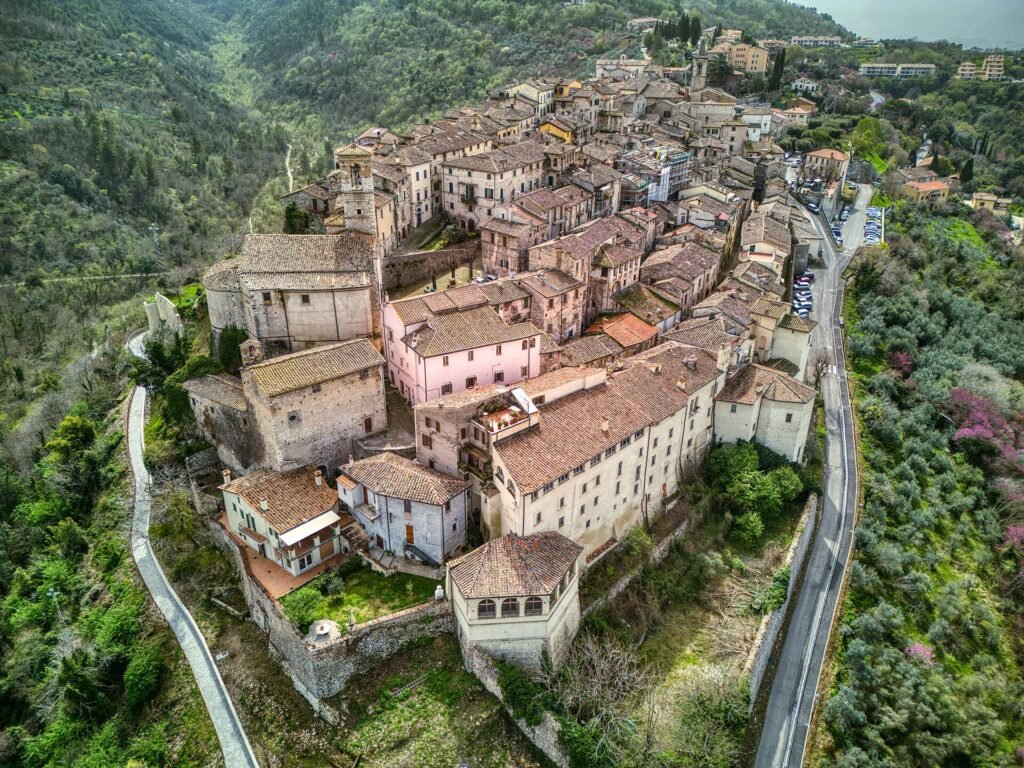 Veduta aerea delle case di pietra di Stroncone su uno stretto crinale, tra una strada tortuosa e versanti boscosi