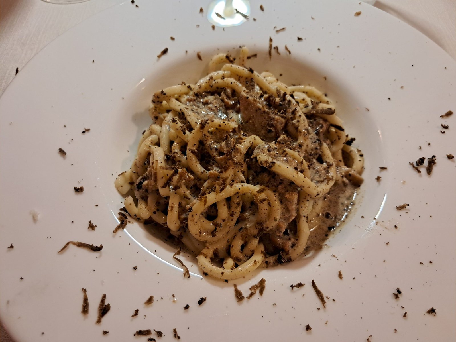 A plate of hand-rolled strozzapreti pasta under a scattering of shaved black truffle