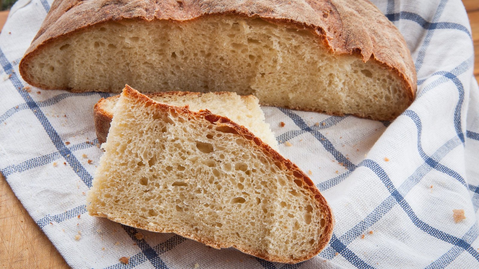 A round loaf of pane sciapo, the unsalted bread of Terni, cut open on a board