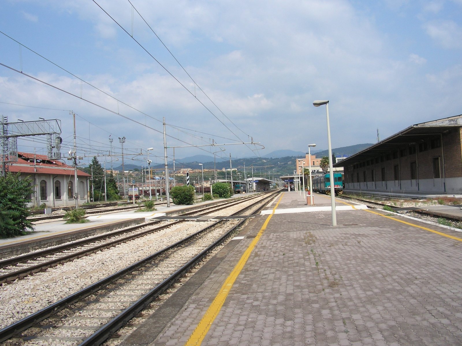 A platform at Terni railway station looking along the tracks, with hills behind