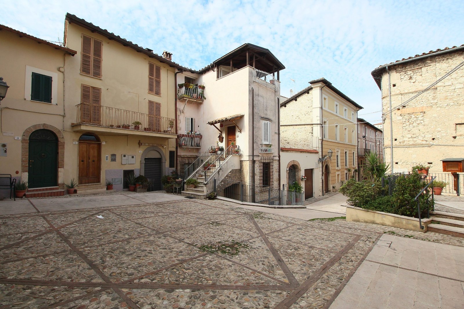 A paved lane inside the village of Torre Orsina, with stone houses, doorways and an external stair