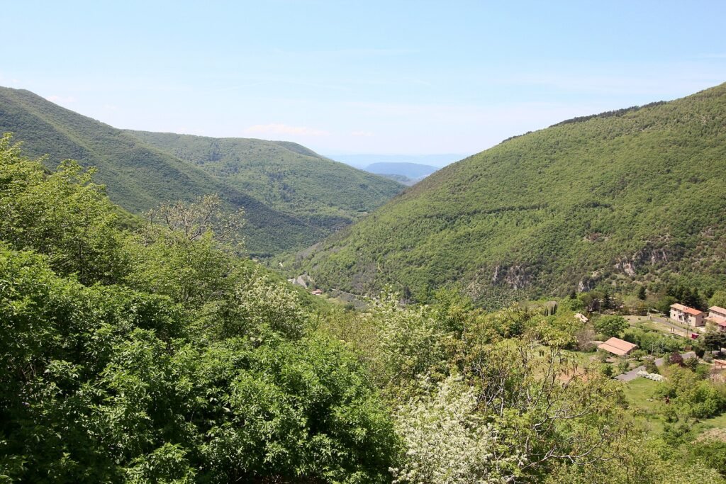Una profonda valle verde tra montagne boscose, vista dall'alto di Polino in una limpida giornata di primavera