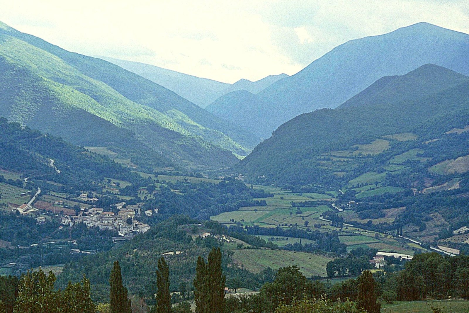 The Valnerina seen from high up, the valley floor in fields with mountain ridges beyond